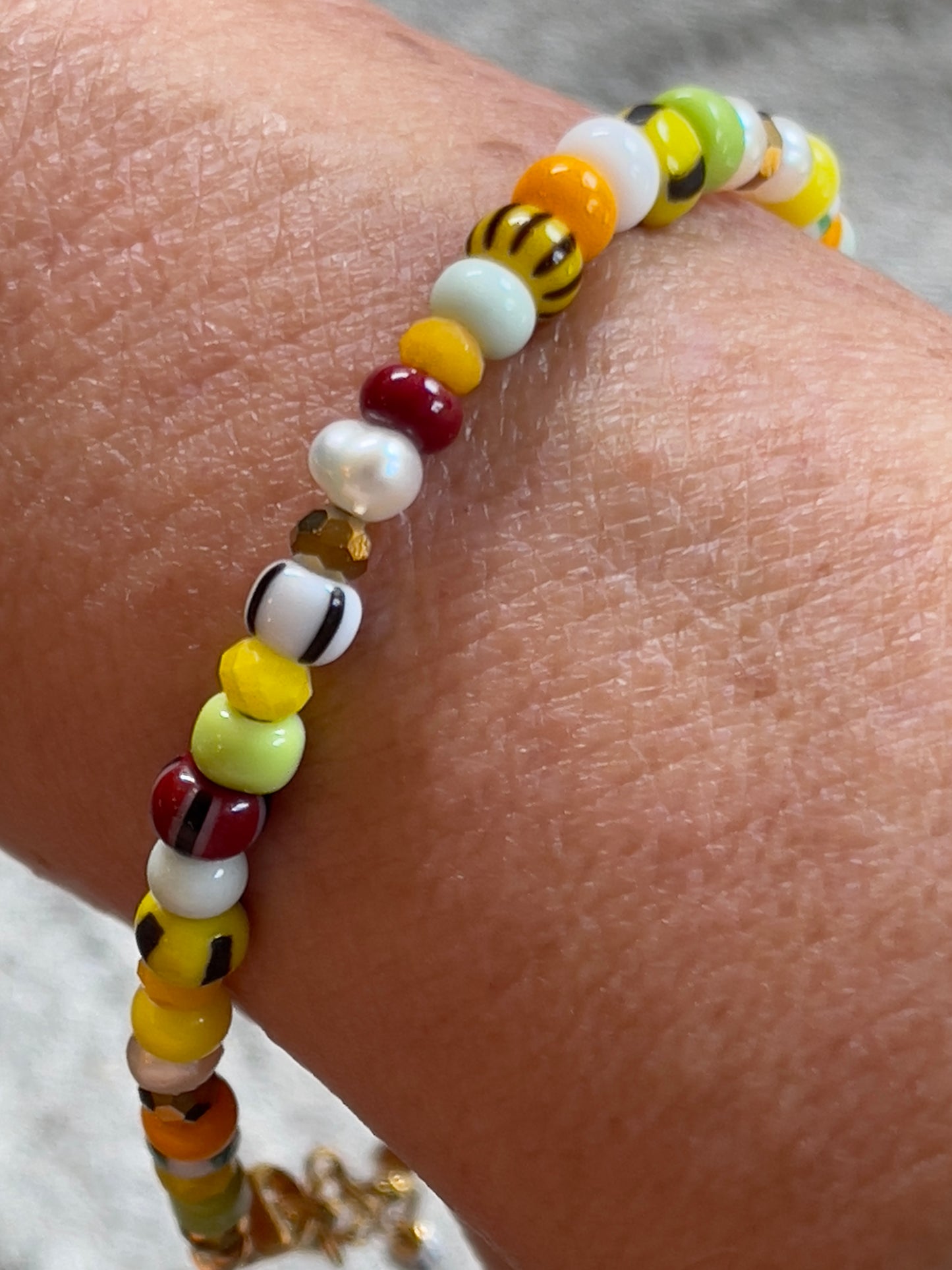 Armbånd med store Seed Beads i lækre gulegrønne, orange og brune nuancer og med små ferskvandsperler