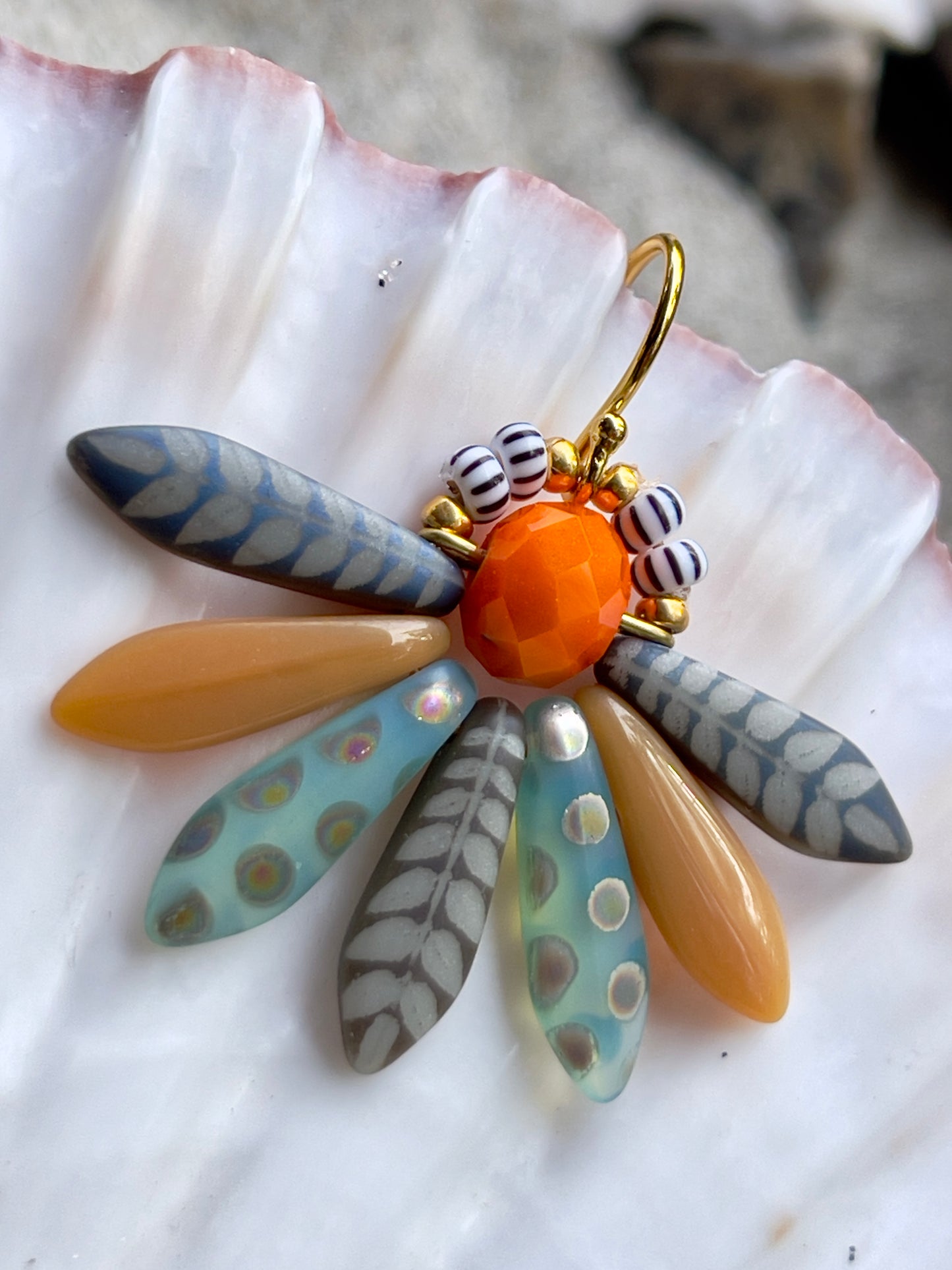 Speciel blomsterørering i blå nuancer med orange glasperle