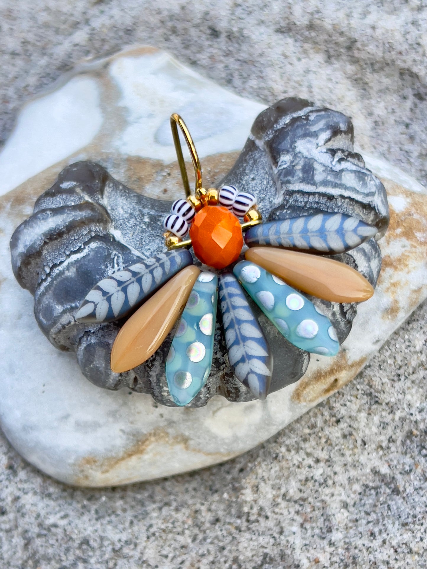 Speciel blomsterørering i blå nuancer med orange glasperle