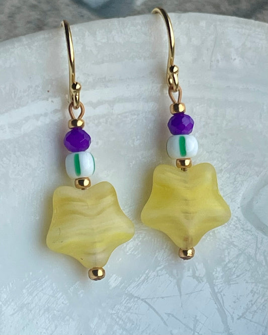 Ørering med flot gul stjerneglasperle, lilla glasperle og grøn og hvid stribet seed beads.