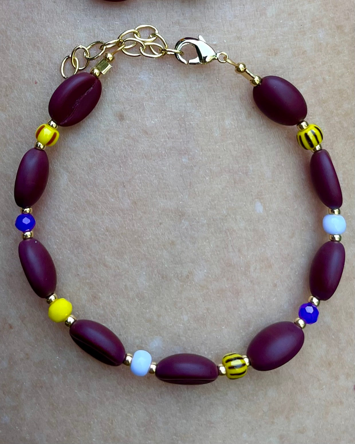 Kaffebønne-armbånd lavet med smukke brune glasperler, kombineret med seed beads og små glasperler i lækre gul og lilla nuancer, der giver et spændende og elegant look.