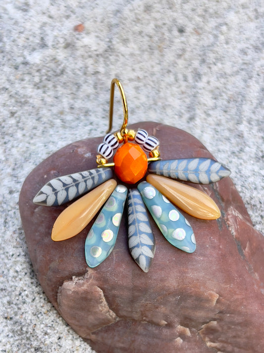 Speciel blomsterørering i blå nuancer med orange glasperle