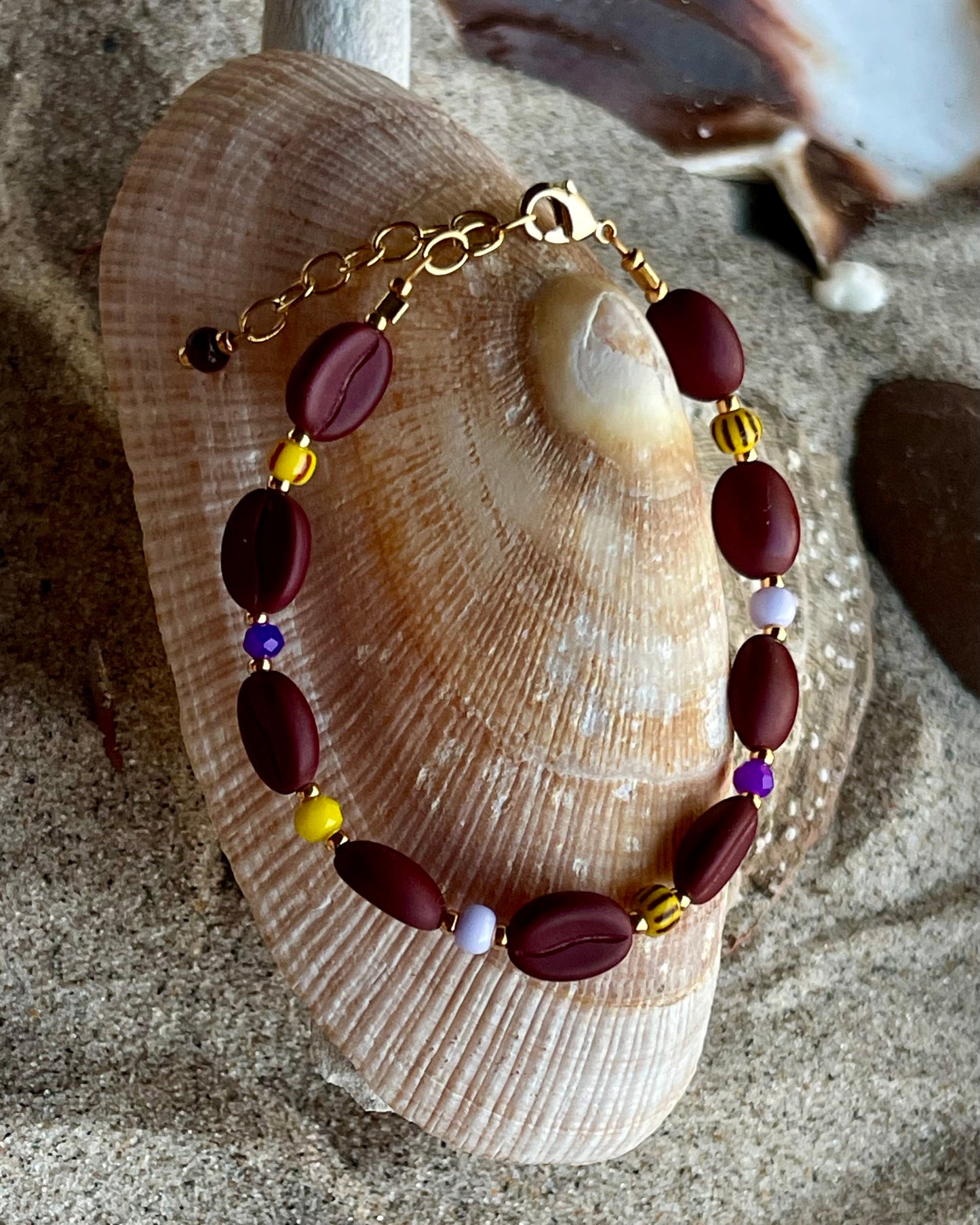Kaffebønne-armbånd lavet med smukke brune glasperler, kombineret med seed beads og små glasperler i lækre gul og lilla nuancer, der giver et spændende og elegant look.