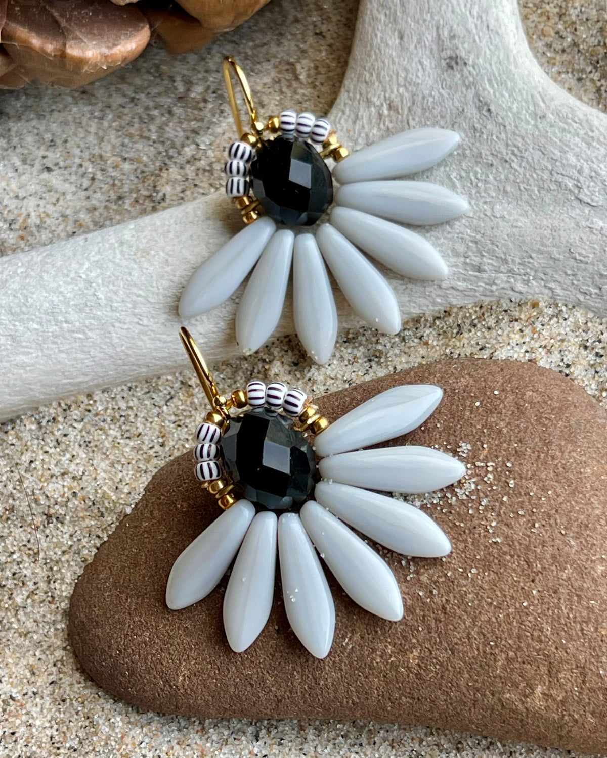 Stor blomsterørering med sort glasperle i midten og fine lysegrå glasperler som blade.