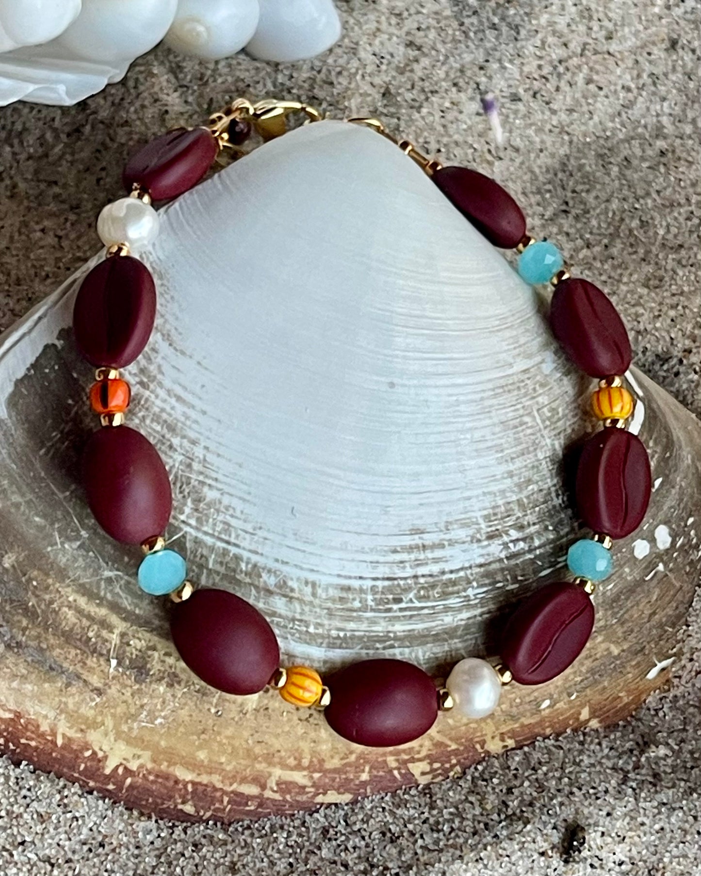 Kaffebønne-armbånd lavet med smukke brune glasperler, kombineret med seed beads og små glasperler i lækre lyseblå og orange nuancer, samt små ferskvandsperler der giver et elegant look.