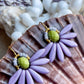 Stor blomster ørering med lys grøn glasperle i midten og med blade af flotte lyse lilla gladperler