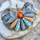 Speciel blomsterørering i blå nuancer med orange glasperle