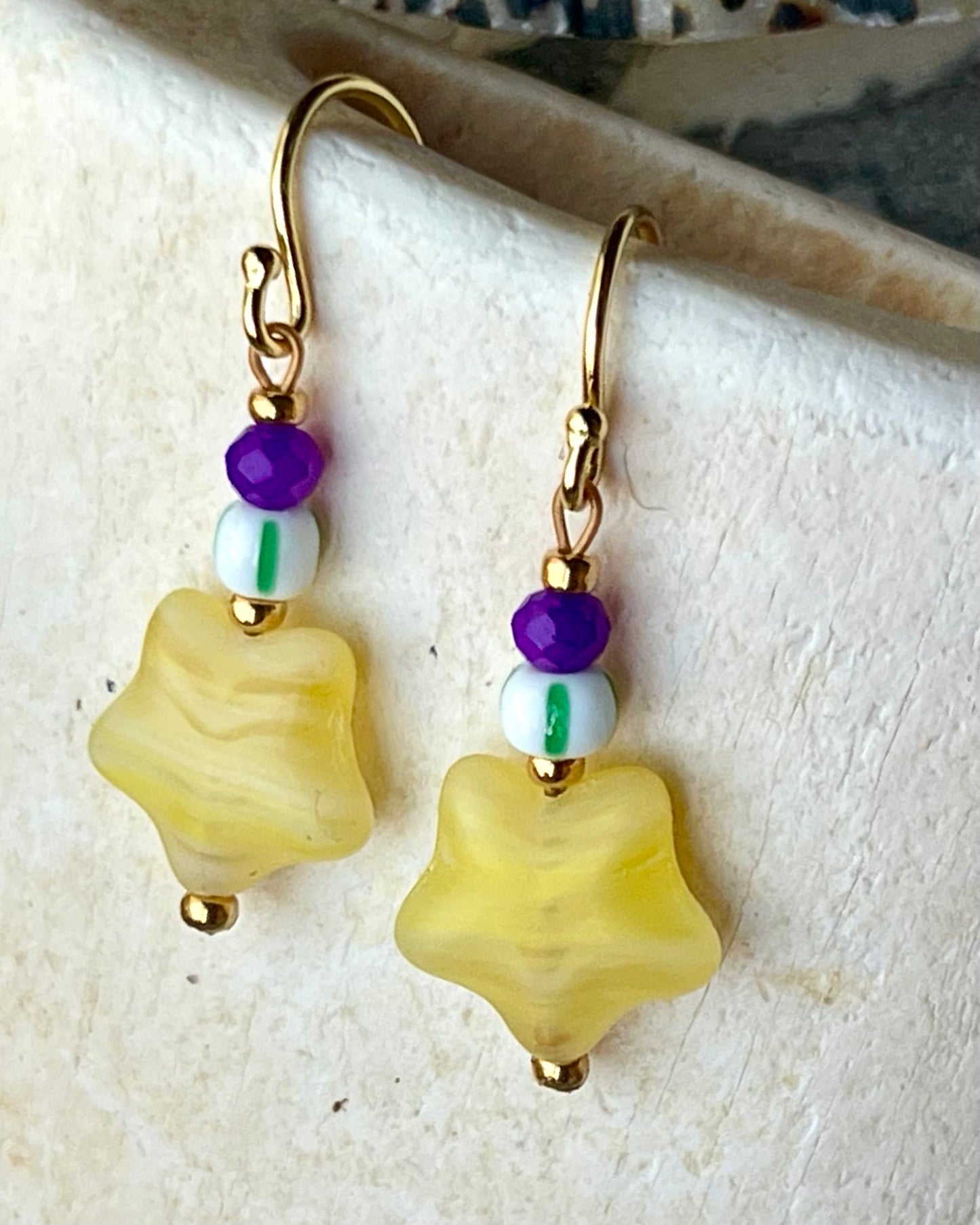Ørering med flot gul stjerneglasperle, lilla glasperle og grøn og hvid stribet seed beads.