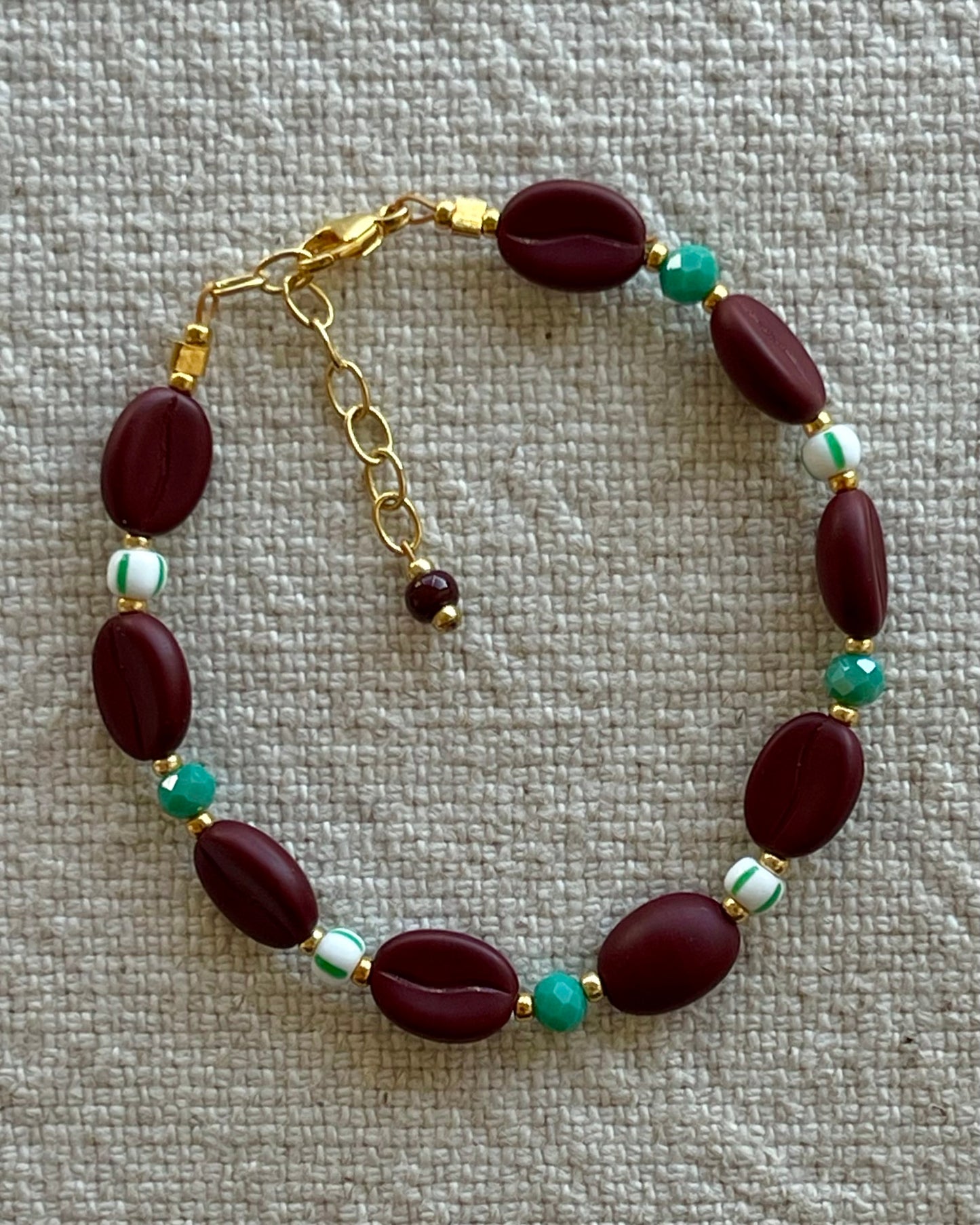 Kaffebønne-armbånd lavet med smukke brune glasperler, kombineret med seed beads og små glasperler i lækre grønne nuancer, der giver et naturligt og elegant look.