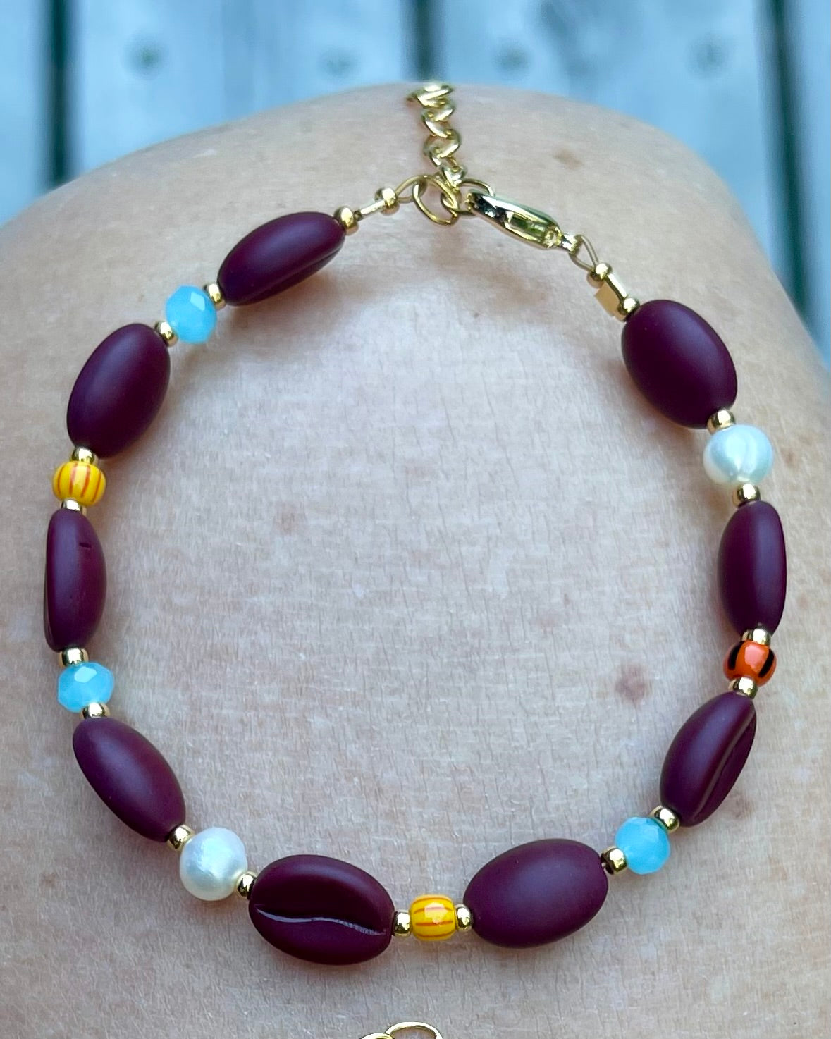 Kaffebønne-armbånd lavet med smukke brune glasperler, kombineret med seed beads og små glasperler i lækre lyseblå og orange nuancer, samt små ferskvandsperler der giver et elegant look.