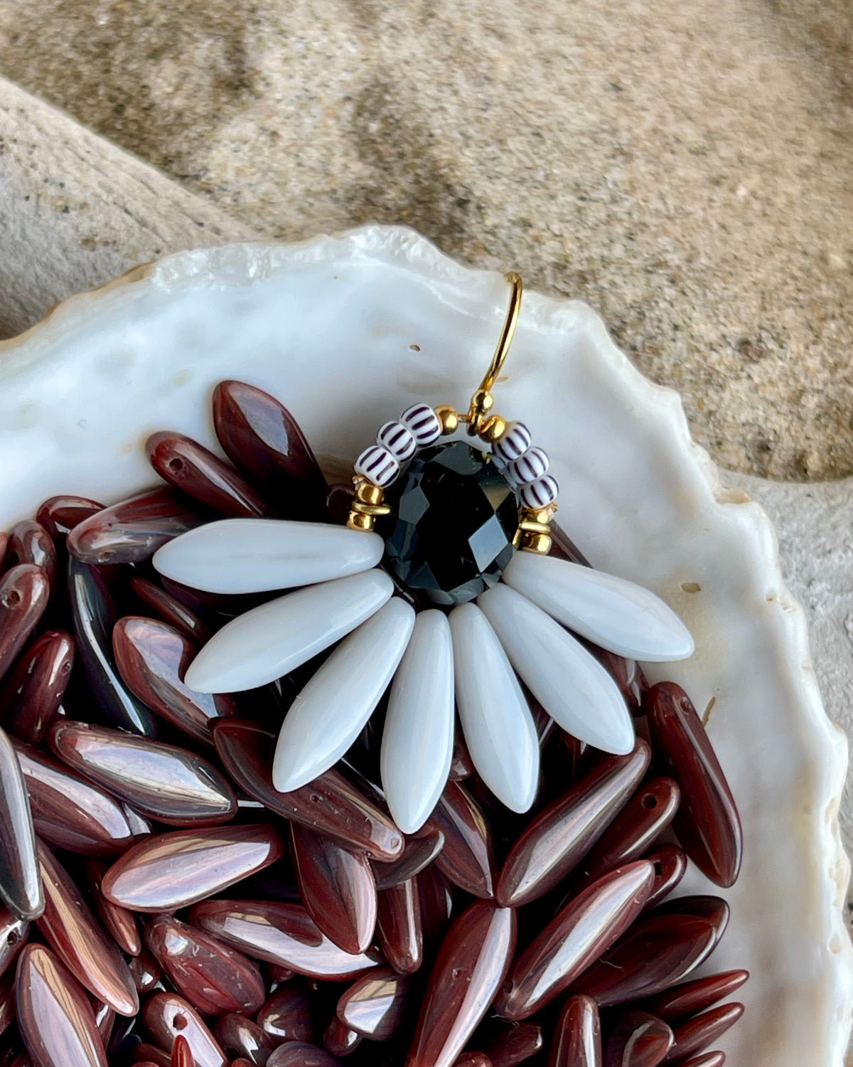 Stor blomsterørering med sort glasperle i midten og fine lysegrå glasperler som blade.