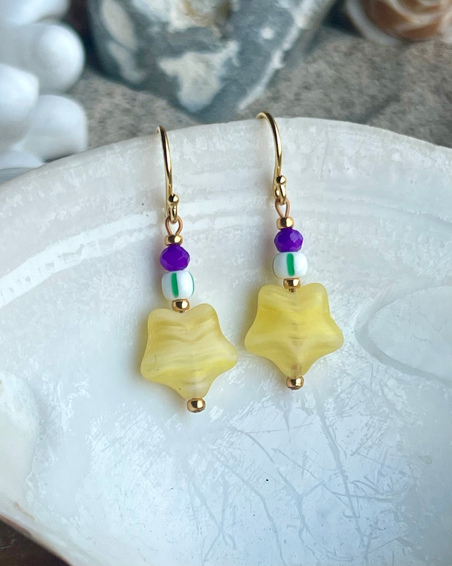 Ørering med flot gul stjerneglasperle, lilla glasperle og grøn og hvid stribet seed beads.