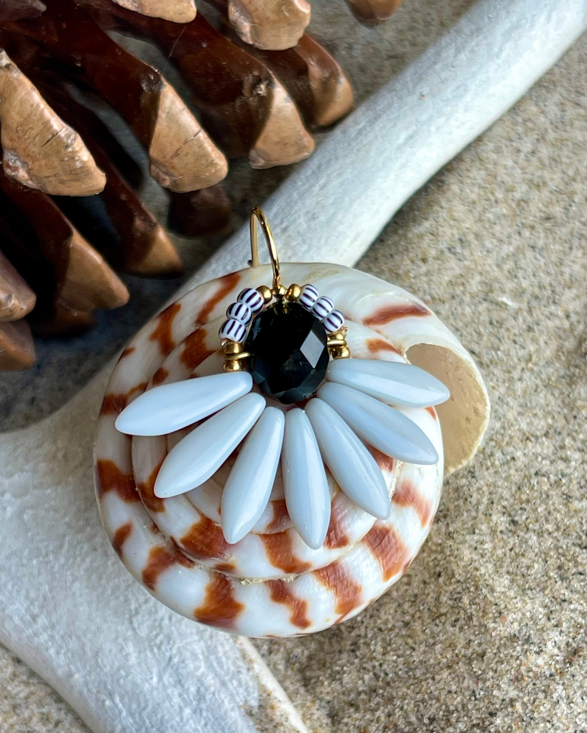 Stor blomsterørering med sort glasperle i midten og fine lysegrå glasperler som blade.