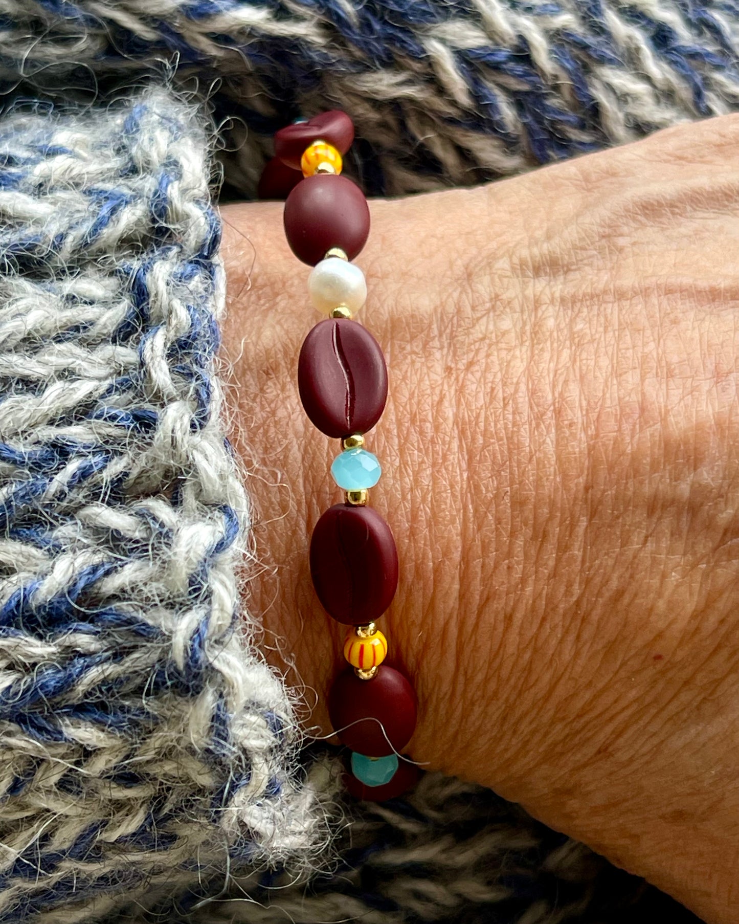 Kaffebønne-armbånd lavet med smukke brune glasperler, kombineret med seed beads og små glasperler i lækre lyseblå og orange nuancer, samt små ferskvandsperler der giver et elegant look.