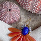 Stor blomsterørering med blade af glasperler ibrændt orange og en flot koboltfarvet glasperle i midten.
